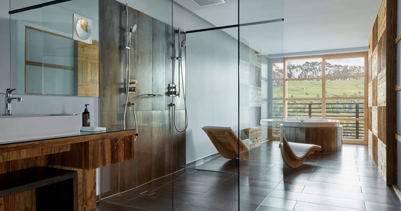 A COMO Alpina bathroom with a walk-in double shower, loungers and a round tub facing the peaks