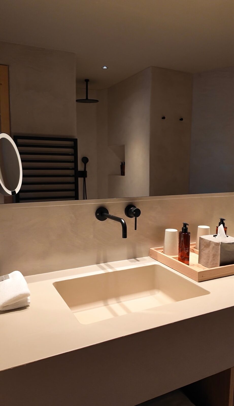 A Forestis tower suite bathroom with a stone basin and black fittings