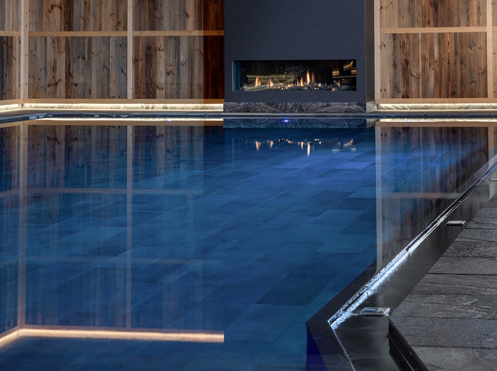 The indoor pool at Gardena Grödnerhof, with reclaimed wood walls and a fireplace