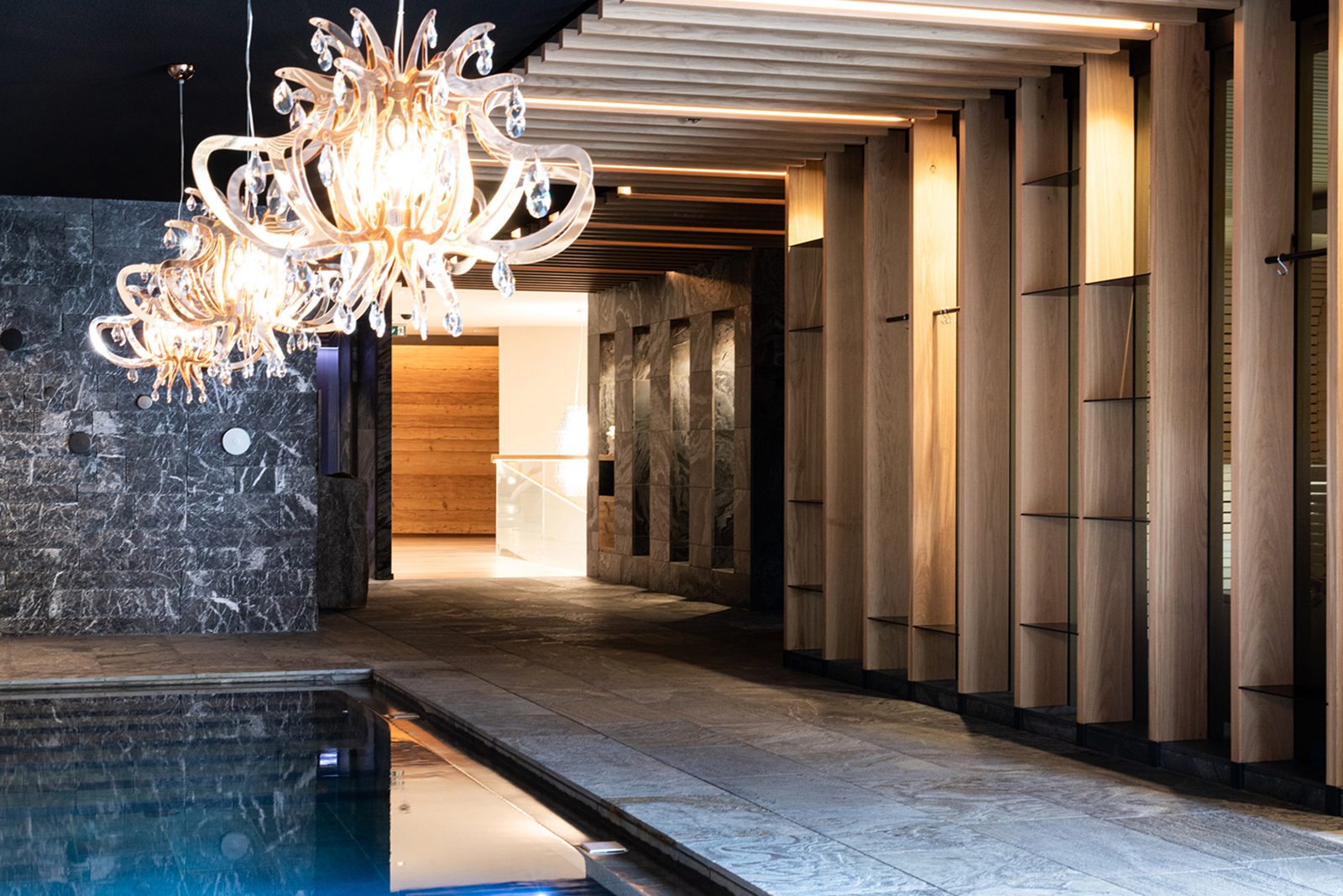 A stone and oak corridor with crystal chandeliers in the Gardena Grödnerhof spa