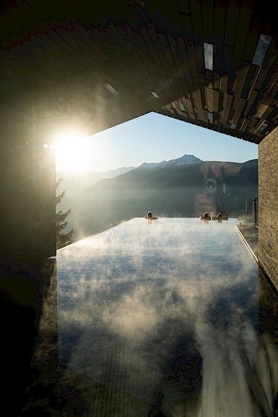 Steam rising off the Miramonti infinity pool at sunrise, with the mountains beyond
