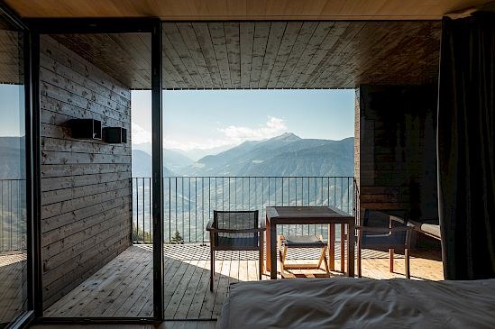 A Miramonti room in dark timber opening onto a balcony above the valley
