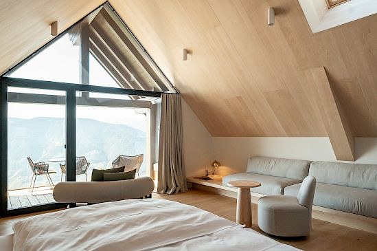 A pale-wood attic room at Miramonti with a gabled window and terrace