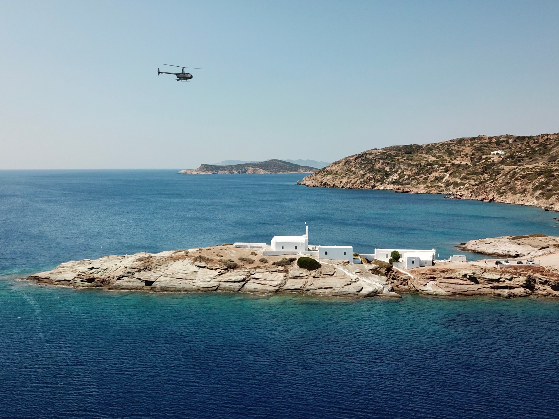 A Hoper helicopter flying over the chapel at Chrissopigi, Sifnos