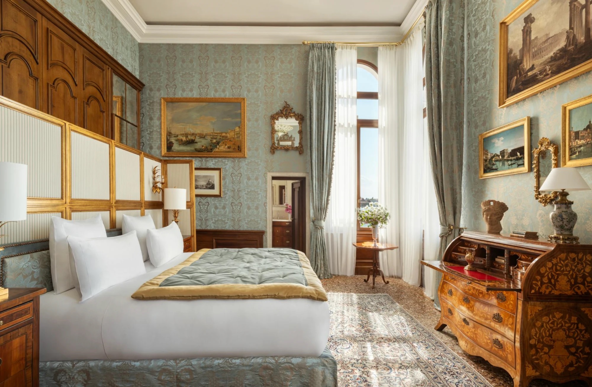 A bedroom in the Suite del Doge at Airelles Palladio with blue silk walls and Venetian paintings