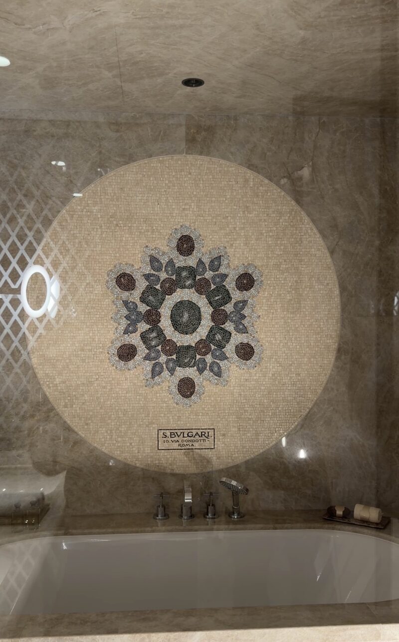 A round stone mosaic above the bathtub in a Bulgari Hotel Roma bathroom, signed S. Bulgari, 10 Via Condotti, Roma