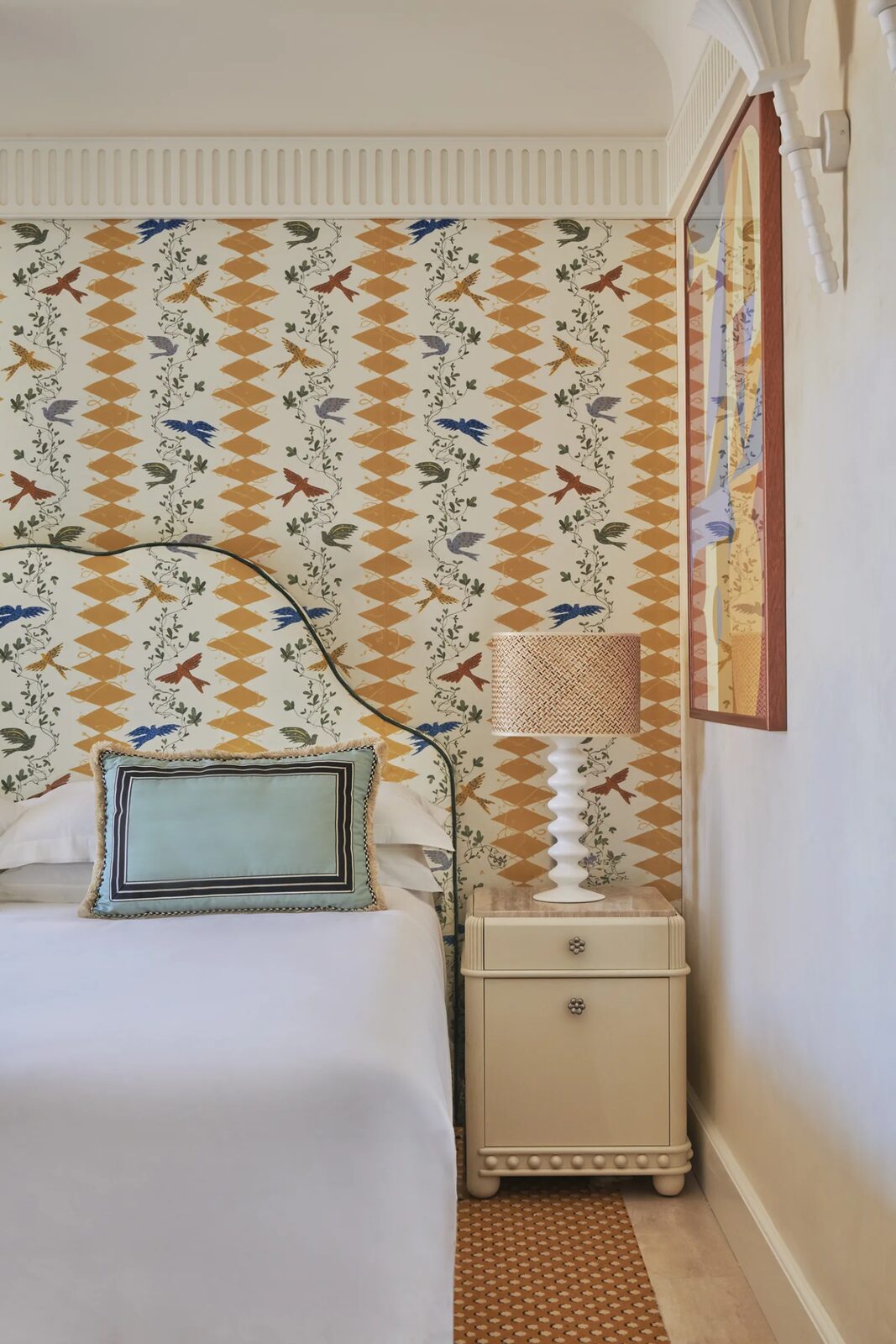 A Casa Monti bed with a curved headboard and wall covered in a bird and harlequin diamond print