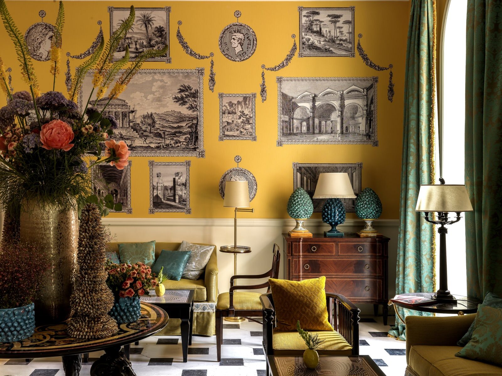 A Hotel de la Ville salon with yellow walls hung with engravings, teal damask curtains and a black and white marble floor