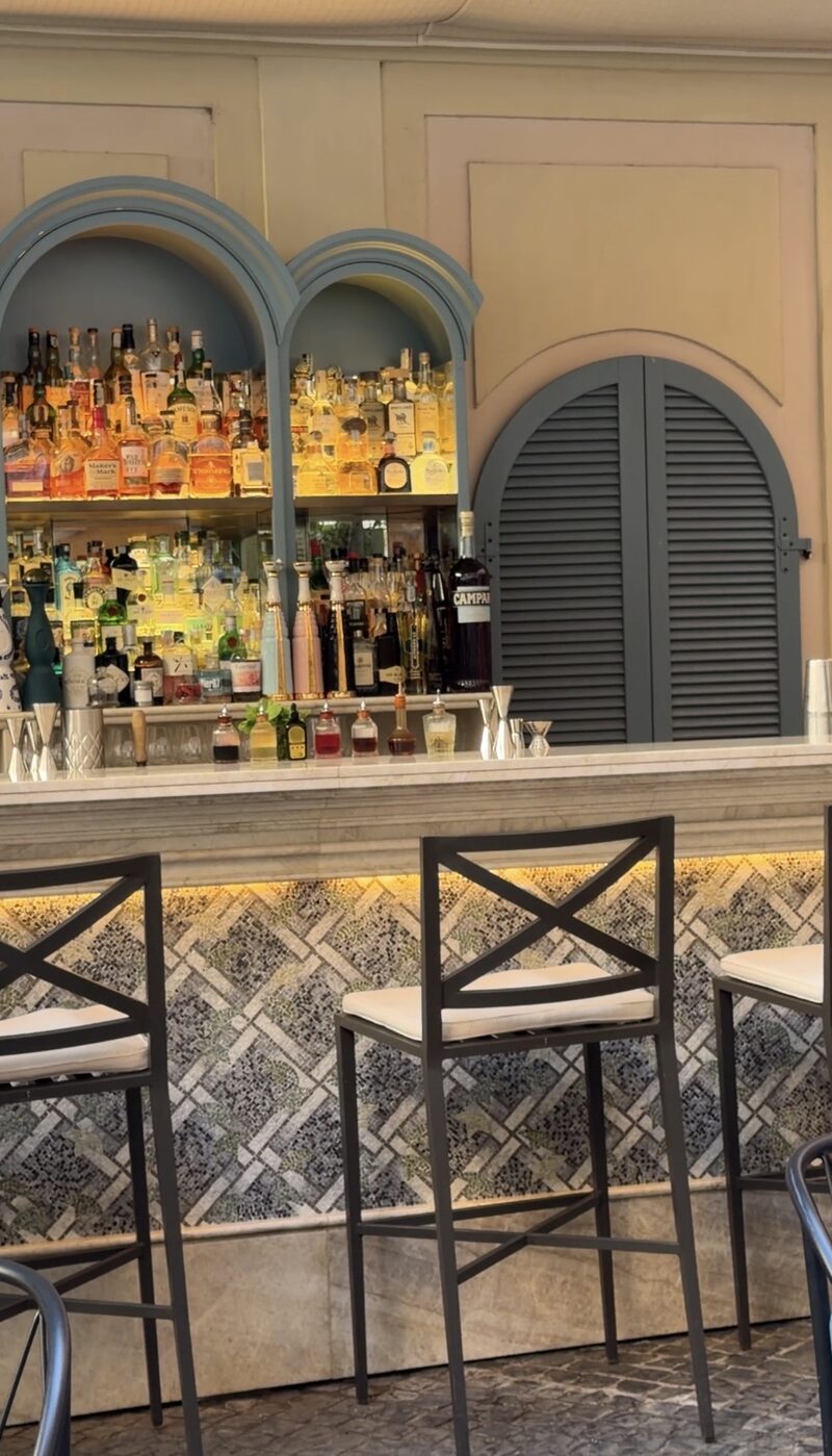 The bar in Hotel de Russie’s courtyard, with arched blue shelves of bottles and a mosaic-fronted marble counter