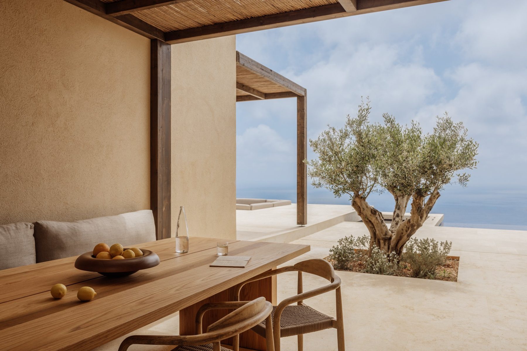 The covered outdoor dining table and olive tree on the Three-Bedroom Villa terrace at Gundari