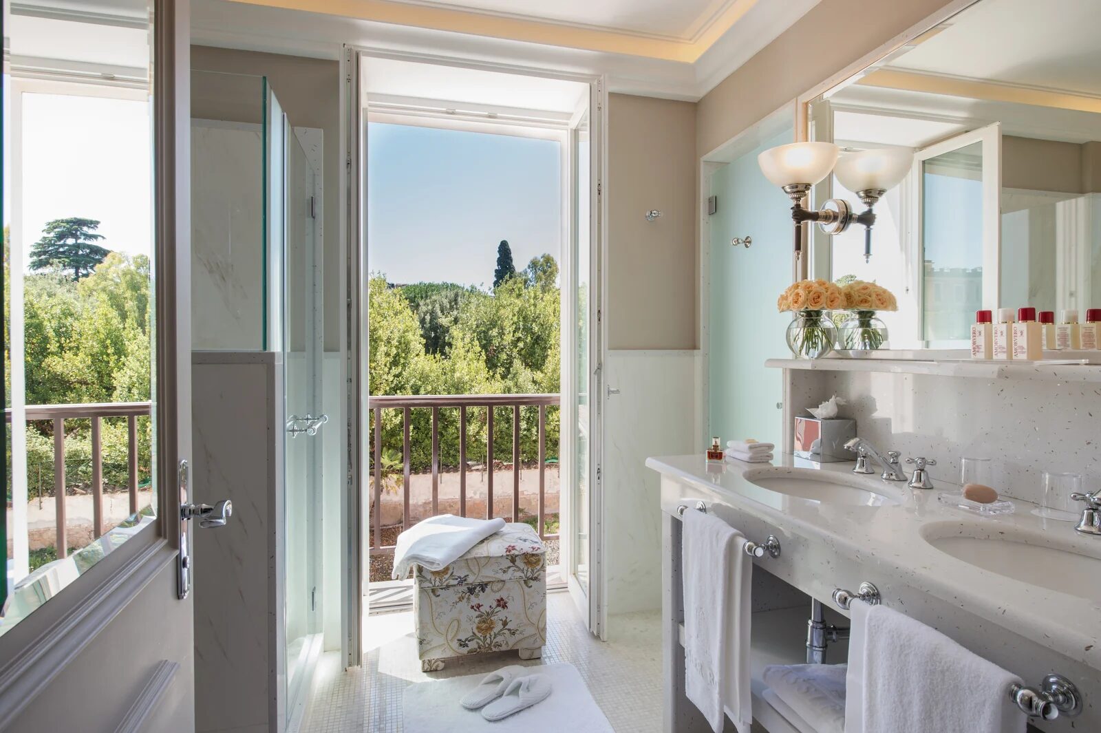 A bright Hotel Hassler Roma bathroom with a double vanity and a balcony door open to the trees