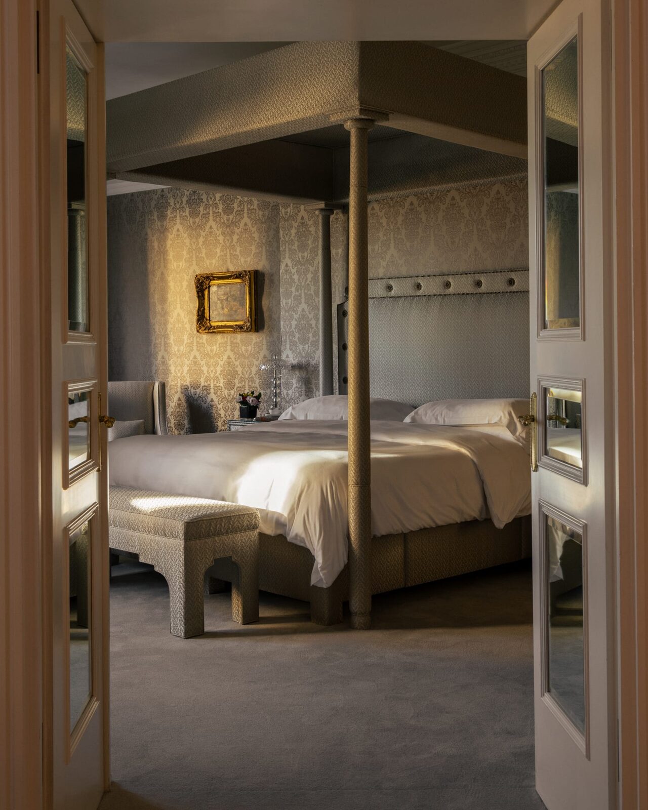 A Hotel Hassler Roma bedroom with a fabric-covered canopy bed, damask walls and a gilded frame