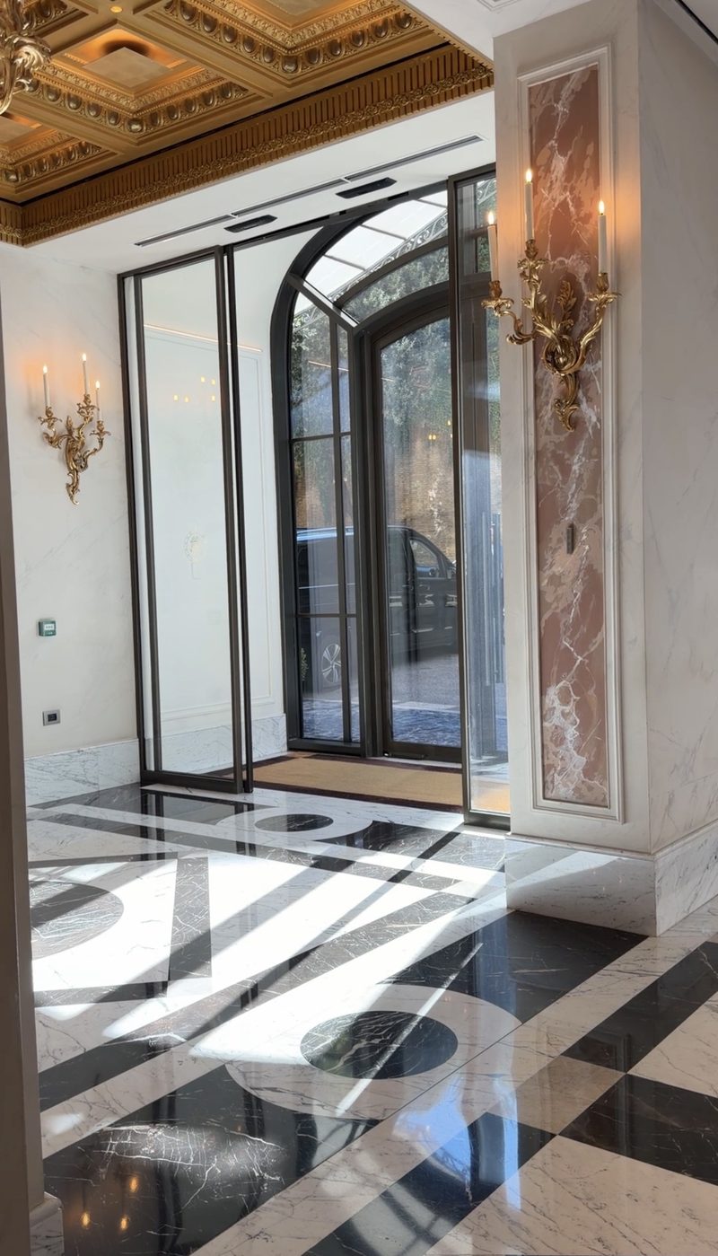 Hotel Eden&rsquo;s entrance hall with a black and white marble floor, gilded sconces and arched glass doors