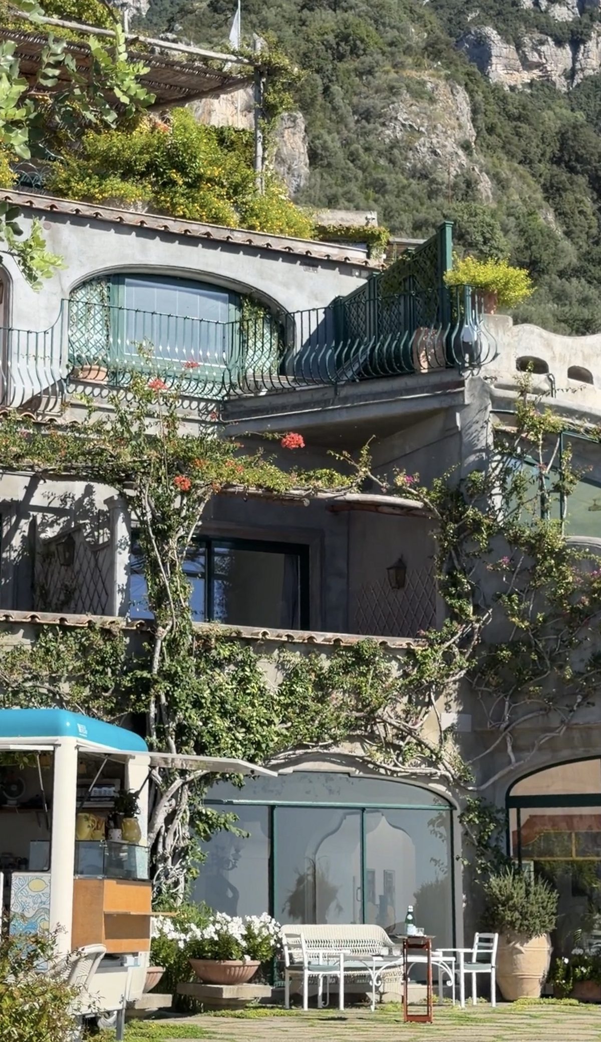 The terraced, vine-covered rooms of Il San Pietro built into the cliff, with green iron balconies