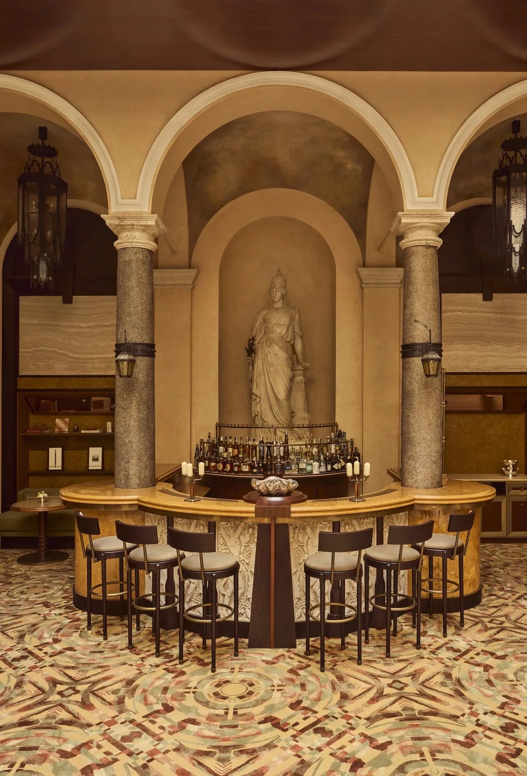 The bar at La Minerva, a curved marble counter beneath a statue of Minerva between granite columns
