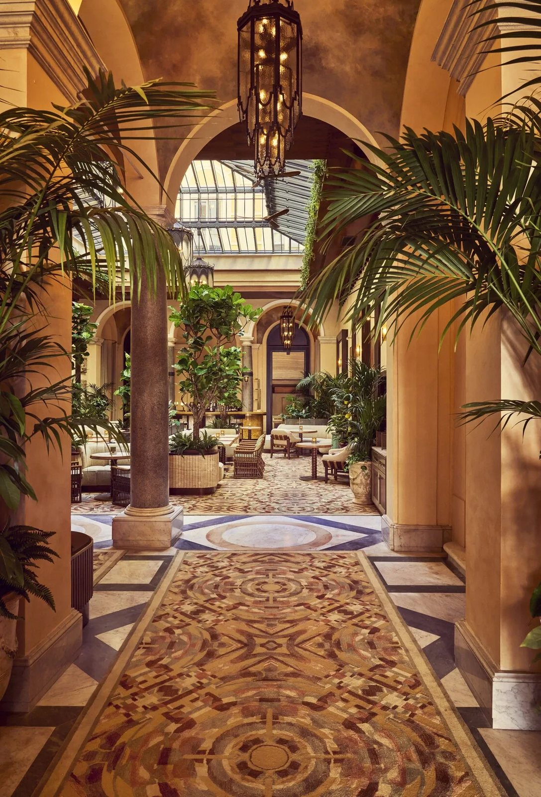 The glass-roofed courtyard at La Minerva, with palms, arches and a mosaic carpet