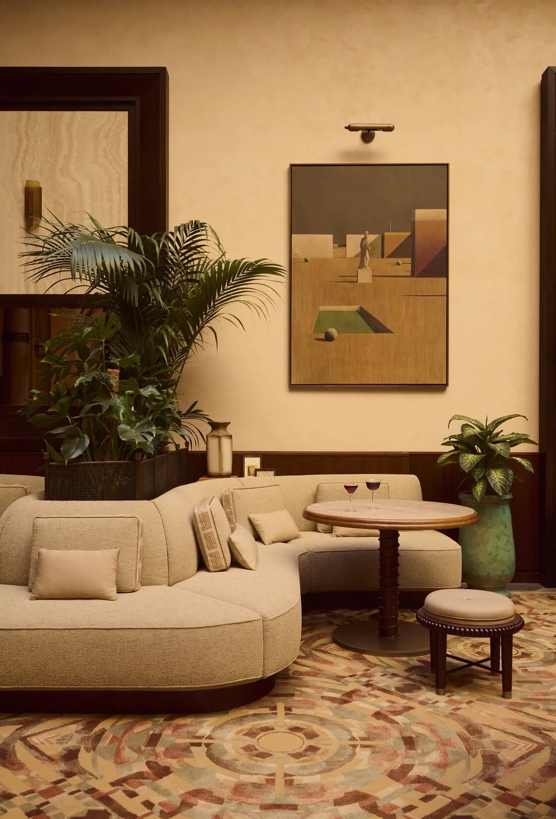 A corner of the lounge with a curved bouclé sofa, palms and two cocktails