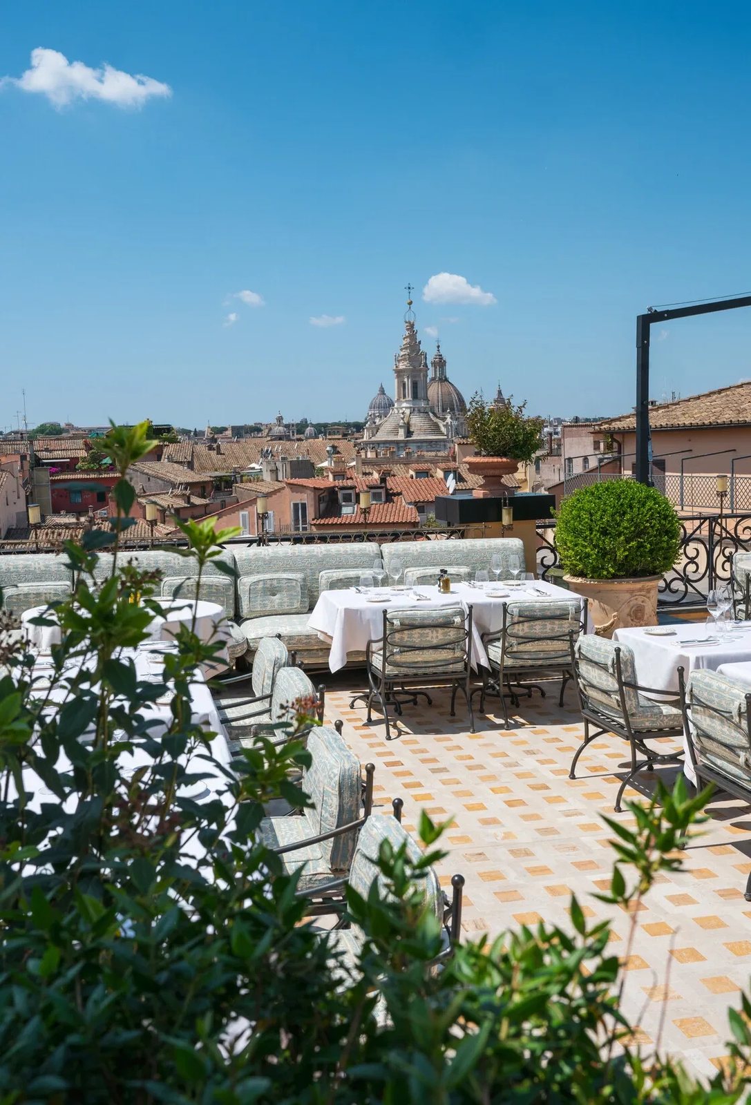 The rooftop terrace at La Minerva with tables set over the terracotta roofs and church domes of Rome