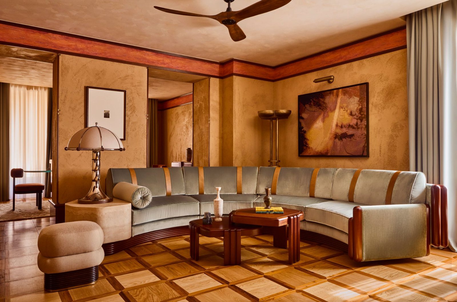 A suite living room at La Minerva, with a curved celadon velvet sofa, parquet floors and Venetian plaster walls