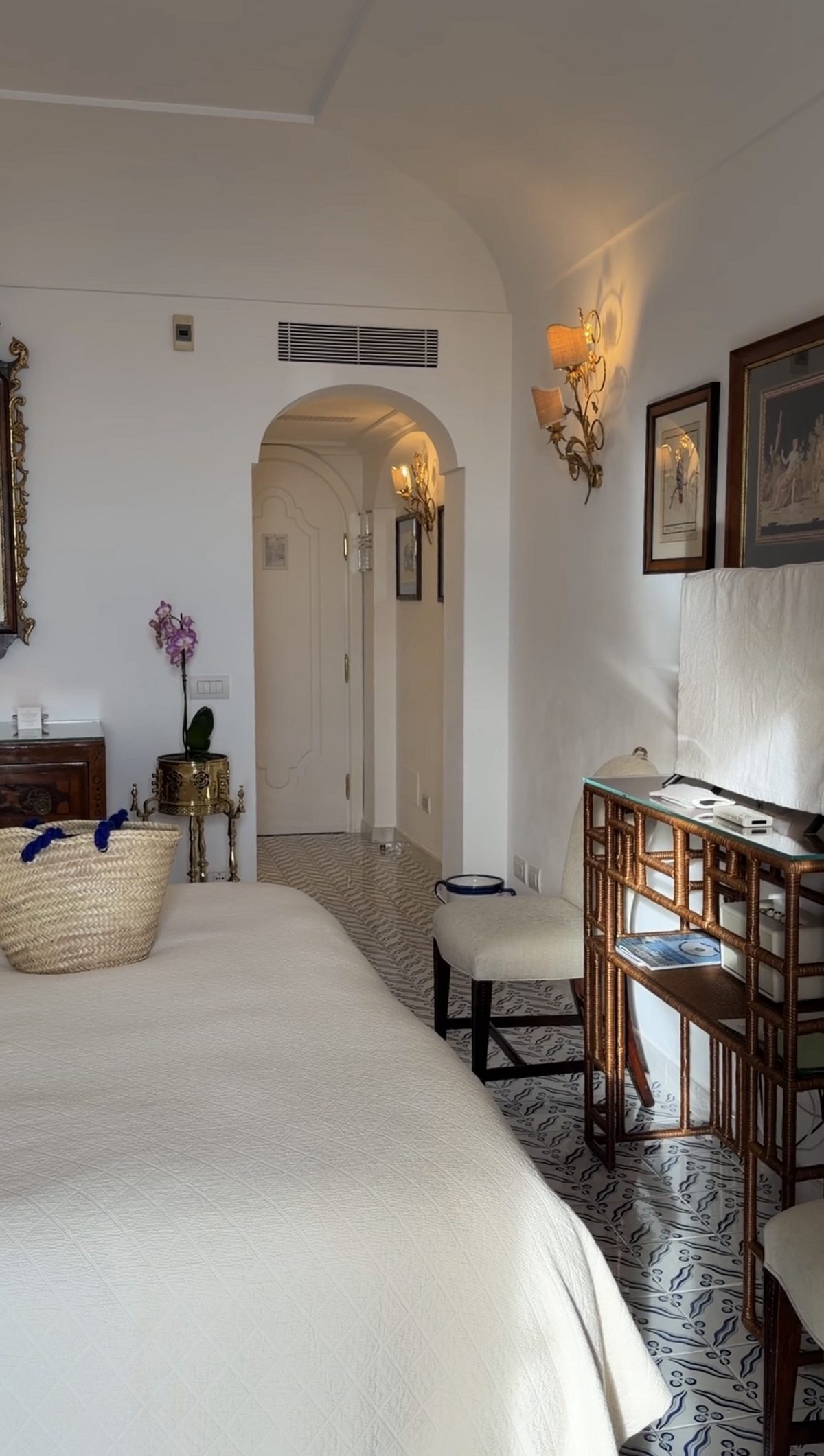 A Le Sirenuse guest room with blue-and-white tiled floors, antique furniture and gilt sconces