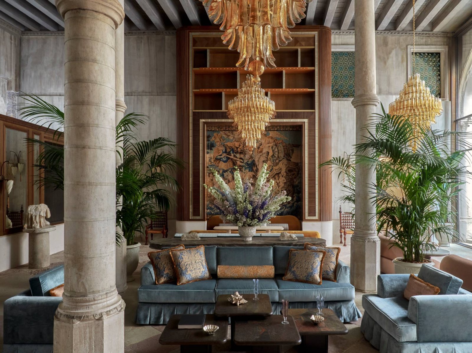 The lobby at Orient Express Venice, with stone columns, Murano chandeliers and blue velvet sofas