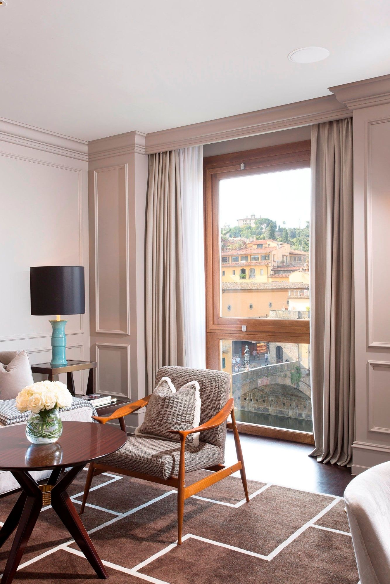 A Portrait Firenze suite living room with a tall window onto the Ponte Vecchio