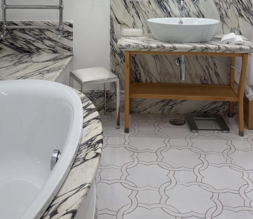 A bold veined-marble bathroom with a vessel sink and soaking tub at Casa Marchesa