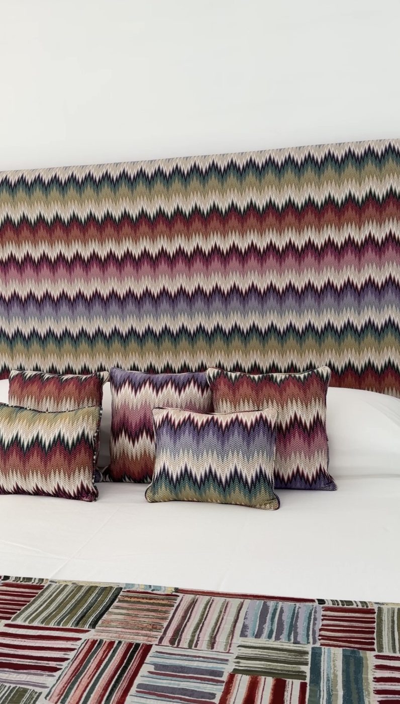 A bed with a bold multicolored zigzag headboard and matching cushions at Casa Marchesa