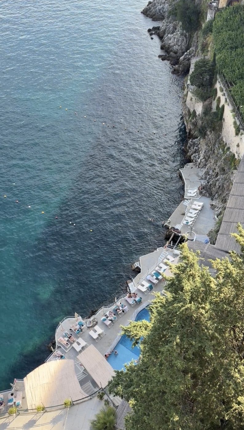 Looking straight down the cliff to the Santa Caterina lido, its pool and loungers at the water's edge