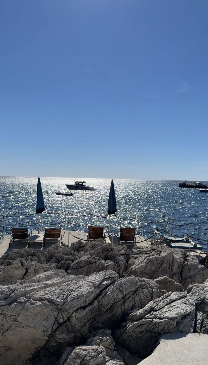 Loungers on the rocks over the sea at the Villa Treville beach club