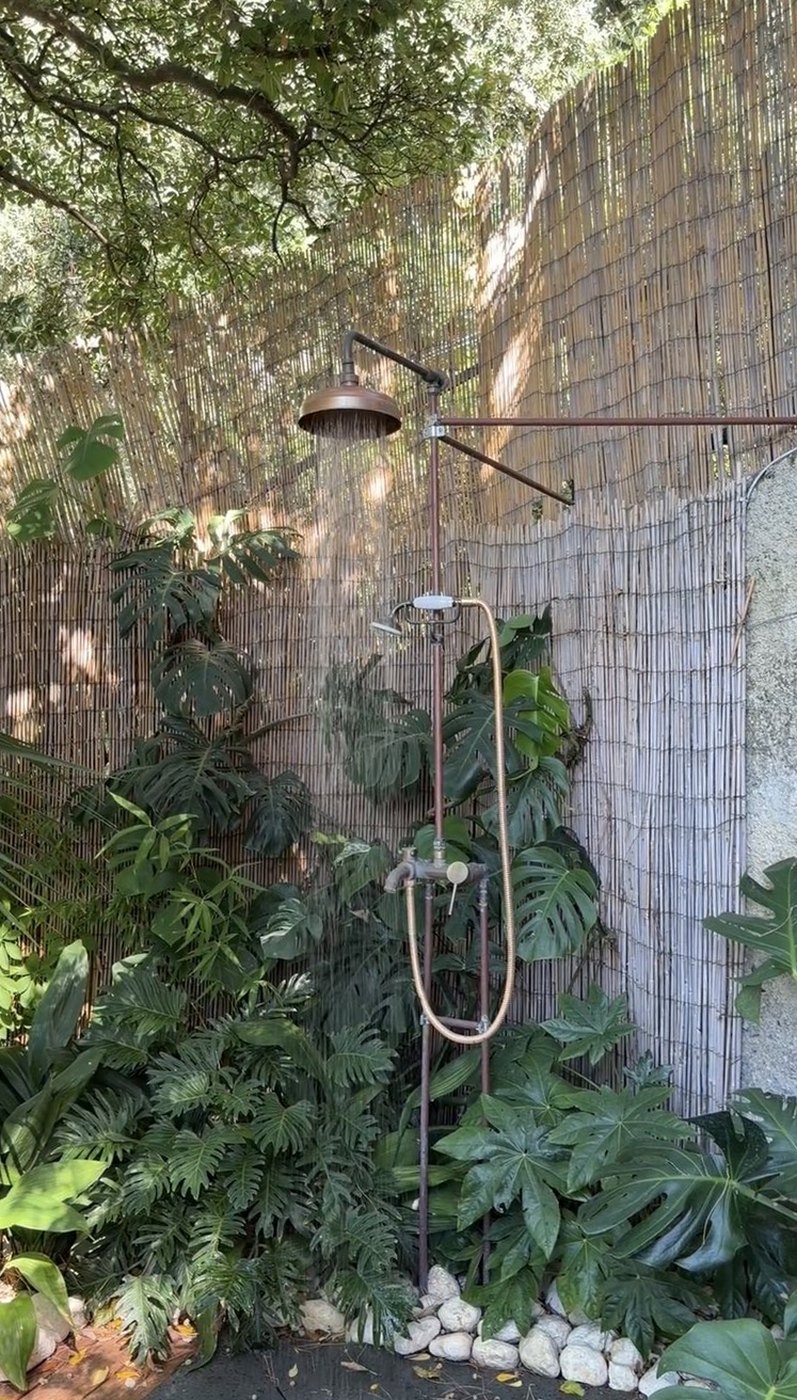 A copper outdoor shower among monstera and palms behind a bamboo screen at Villa Treville