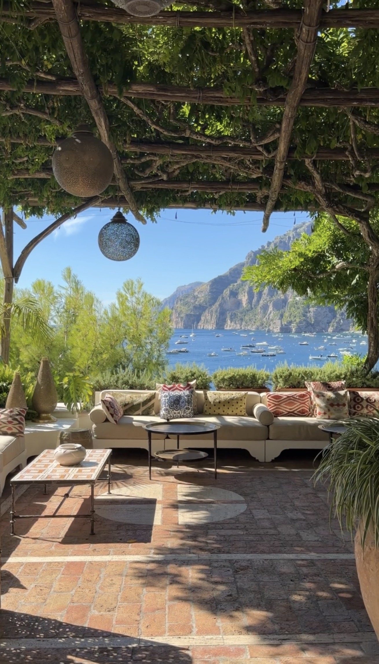 A wisteria-covered terrace lounge at Villa Treville looking across the bay to Positano