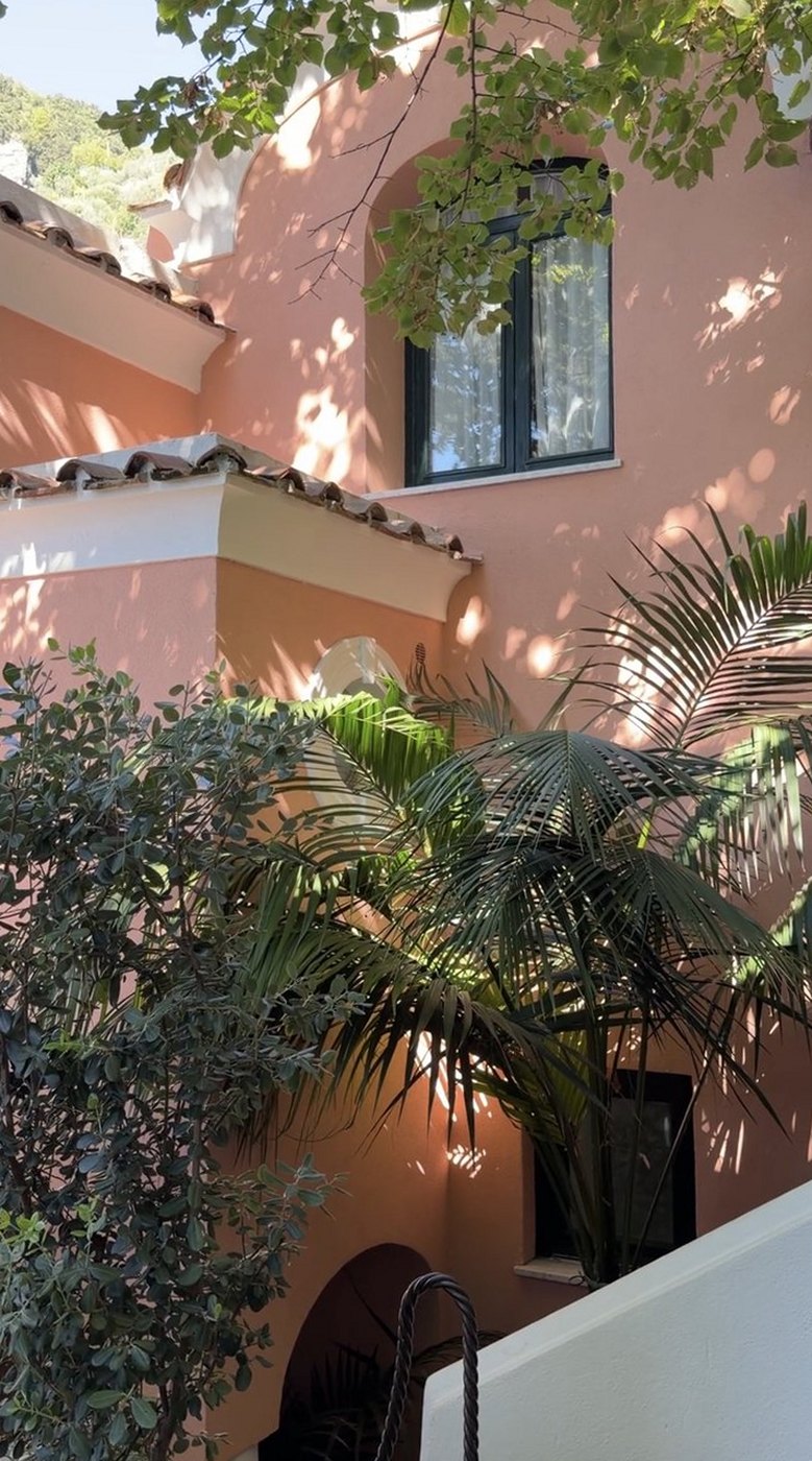 A pink villa with arched windows and palms at Villa Treville