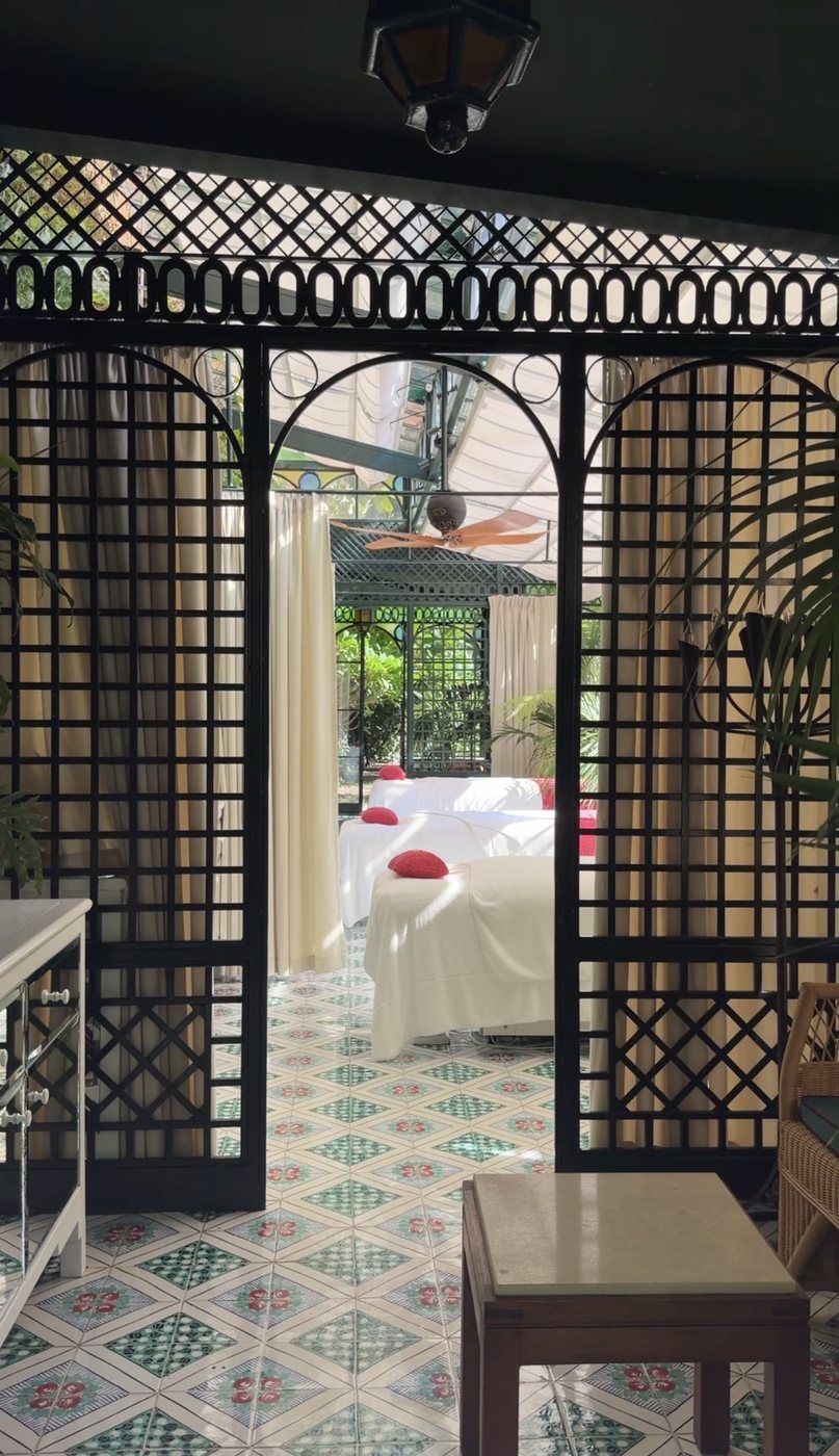Treatment beds behind black iron lattice screens on hand-painted tiles in the Villa Treville spa