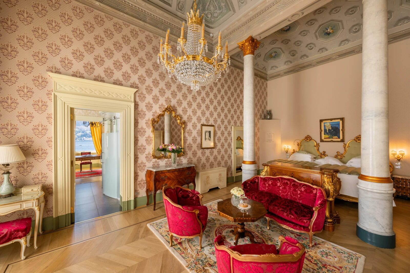 A suite at Villa Serbelloni with a chandelier, frescoed ceiling and red velvet furniture