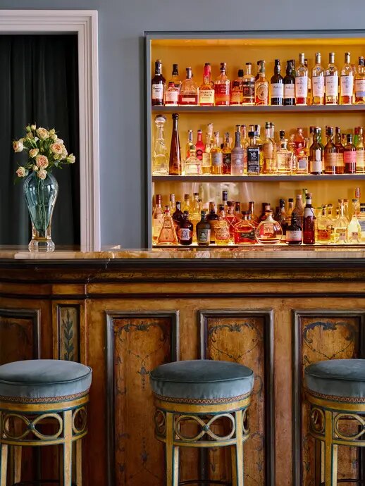 The bar at Grand Hotel Miramare, a painted wooden counter with velvet stools in front of a lit wall of bottles