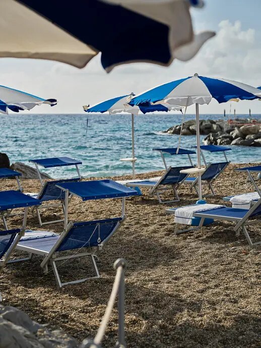 Blue and white umbrellas and loungers on the pebble beach at the Grand Hotel Miramare beach club