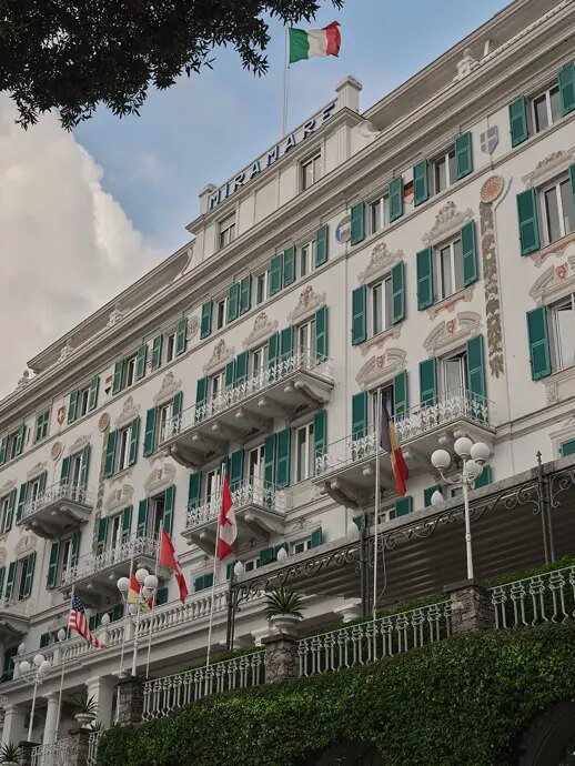 The white Belle Époque facade of Grand Hotel Miramare with green shutters, painted details and wrought-iron balconies