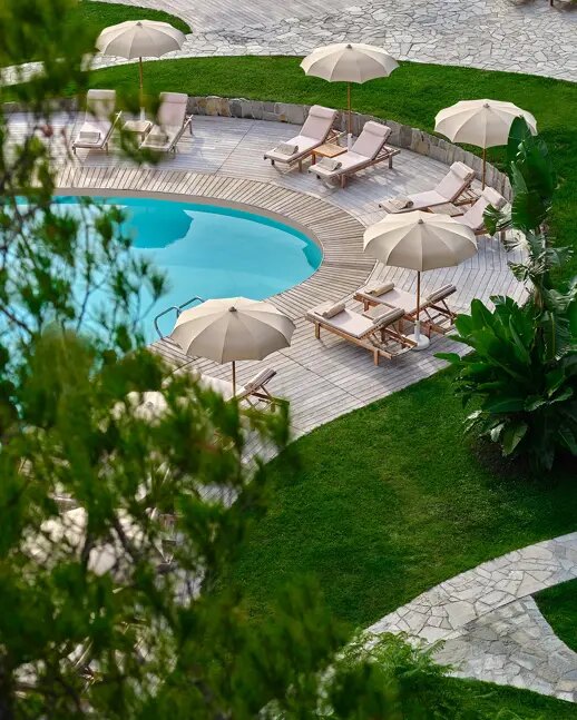 The curved pool at Grand Hotel Miramare, ringed by loungers and white umbrellas on a lawn