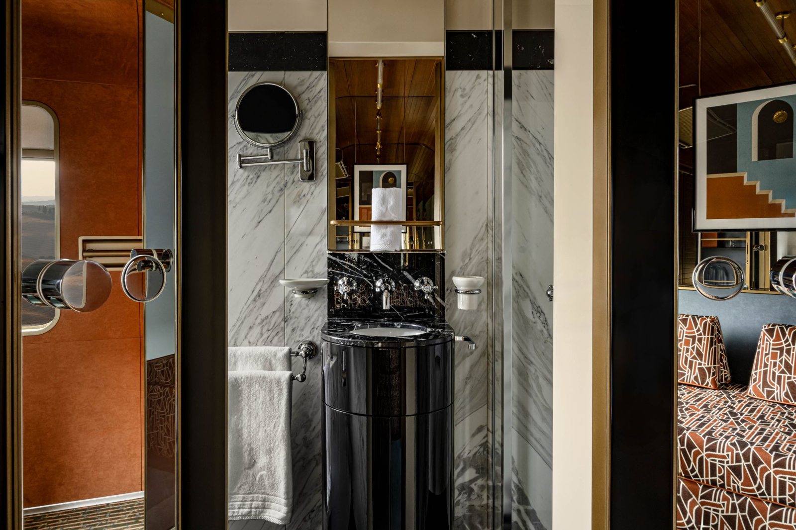 A private cabin bathroom in white and black marble with a lacquered pedestal sink