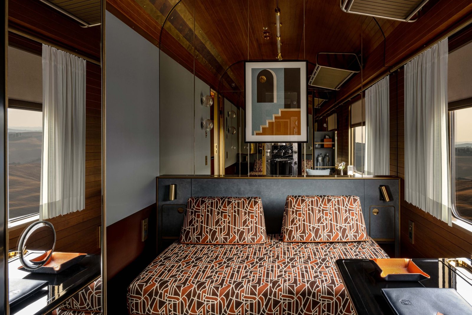 A La Dolce Vita cabin with a patterned daybed, wood paneling and windows on both sides