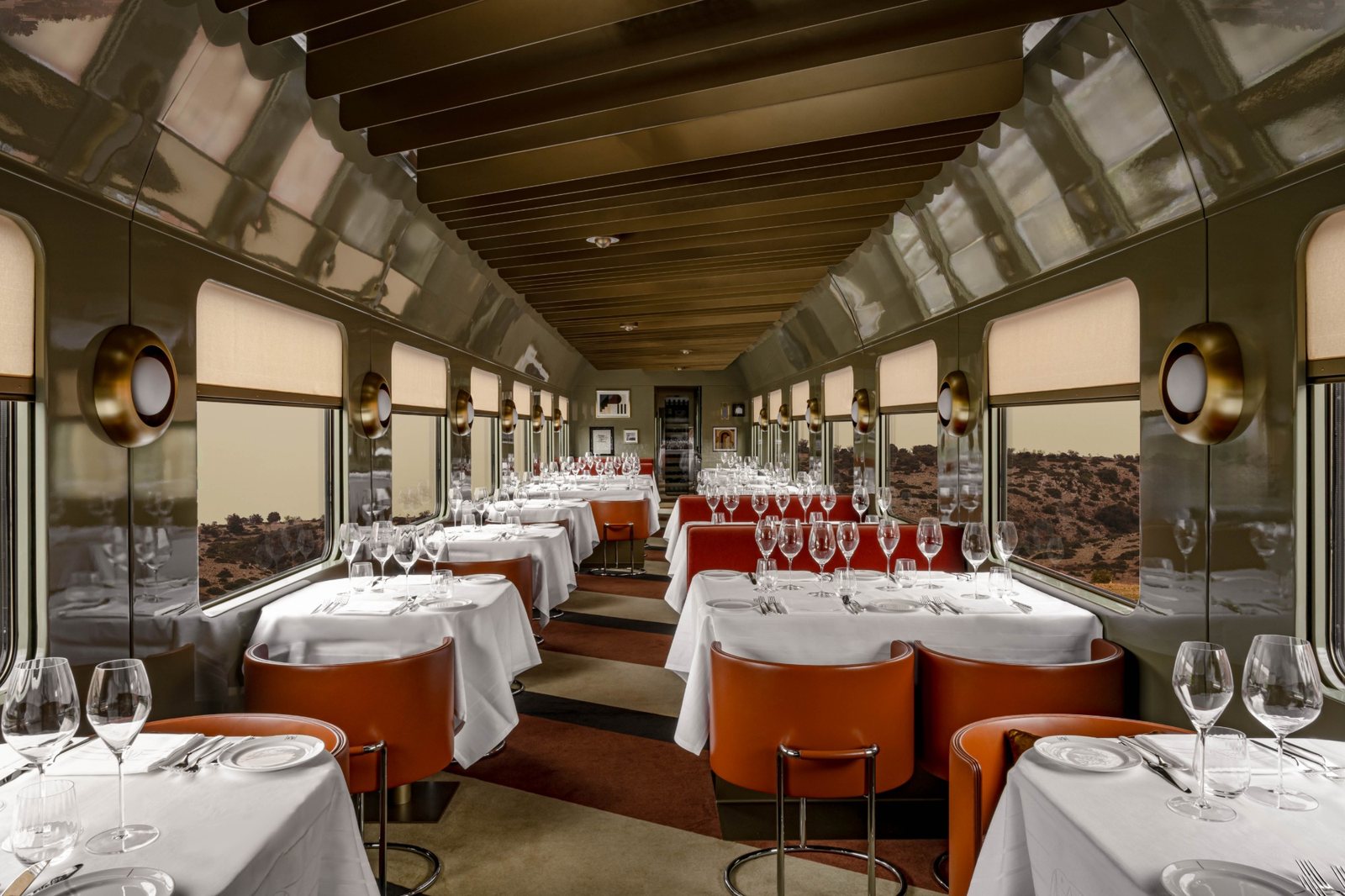 The La Dolce Vita dining car, white-linen tables and orange leather chairs beneath a lacquered ceiling