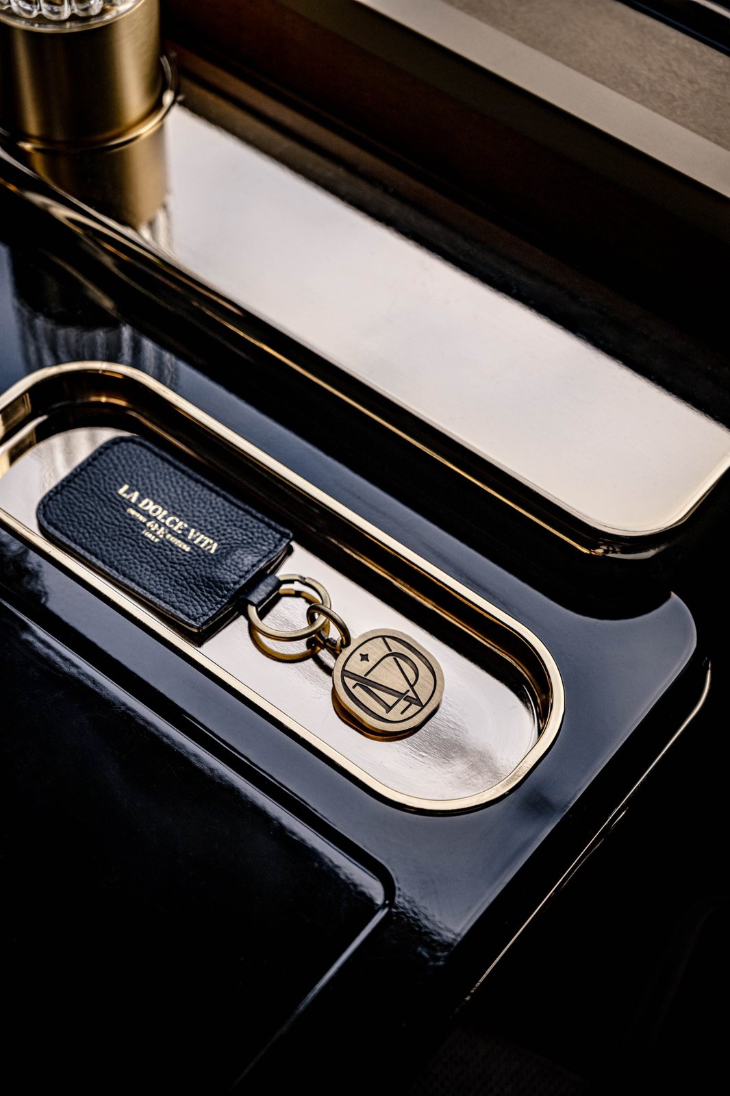 A leather and brass La Dolce Vita cabin key in a lacquered tray