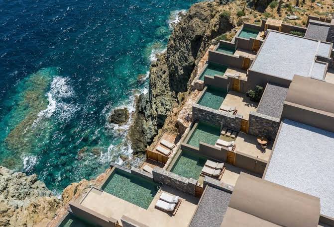 Terraced suites with private pools stepping down the cliff above the sea at Acro Suites