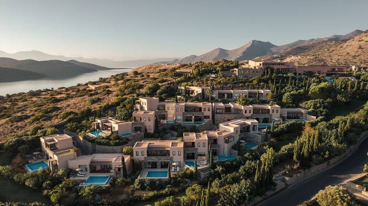Villas with private pools stepping down a green hillside above the gulf at Phaea Blue, Elounda