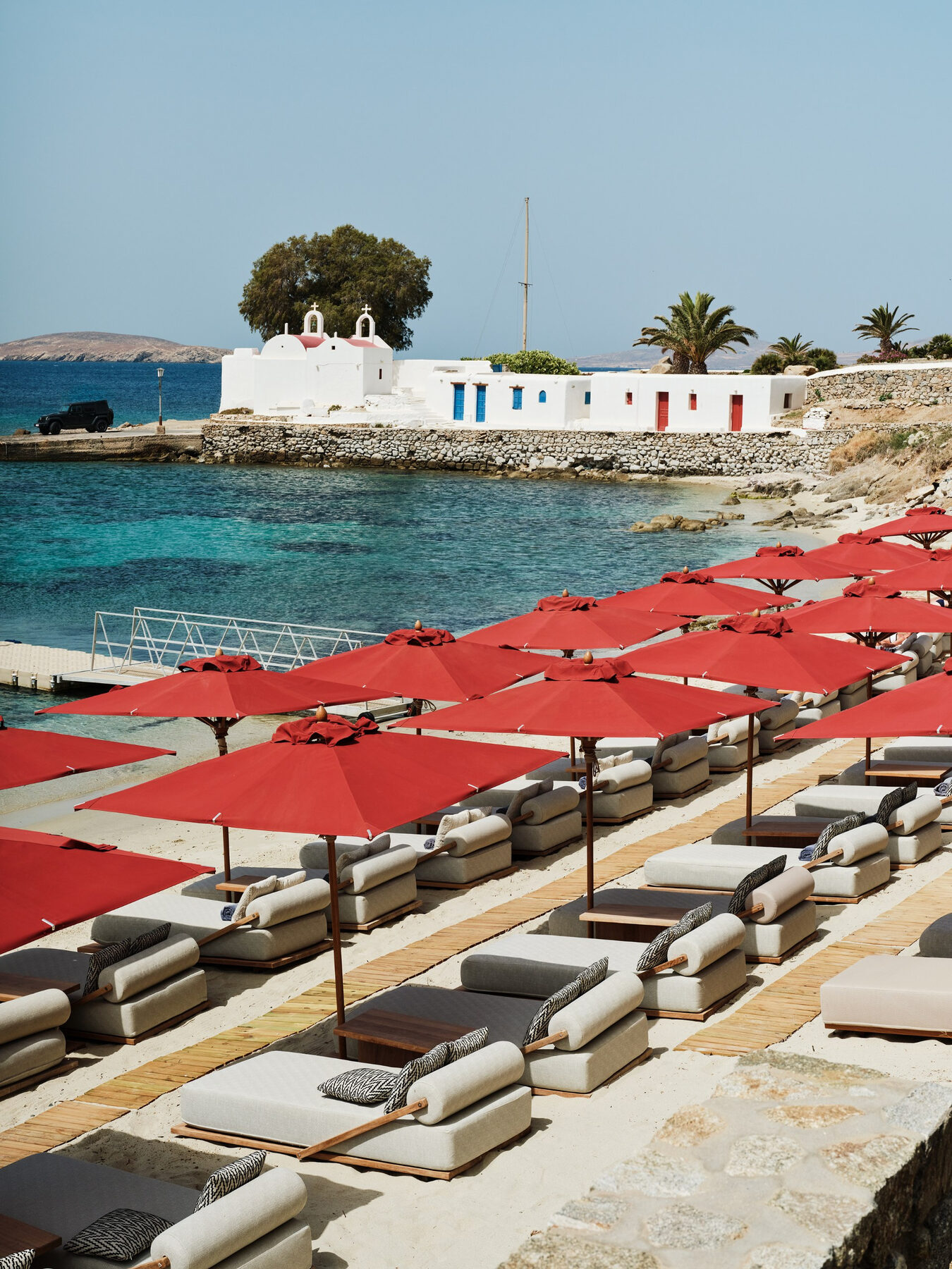 Red umbrellas and daybeds on a private Mykonos beach