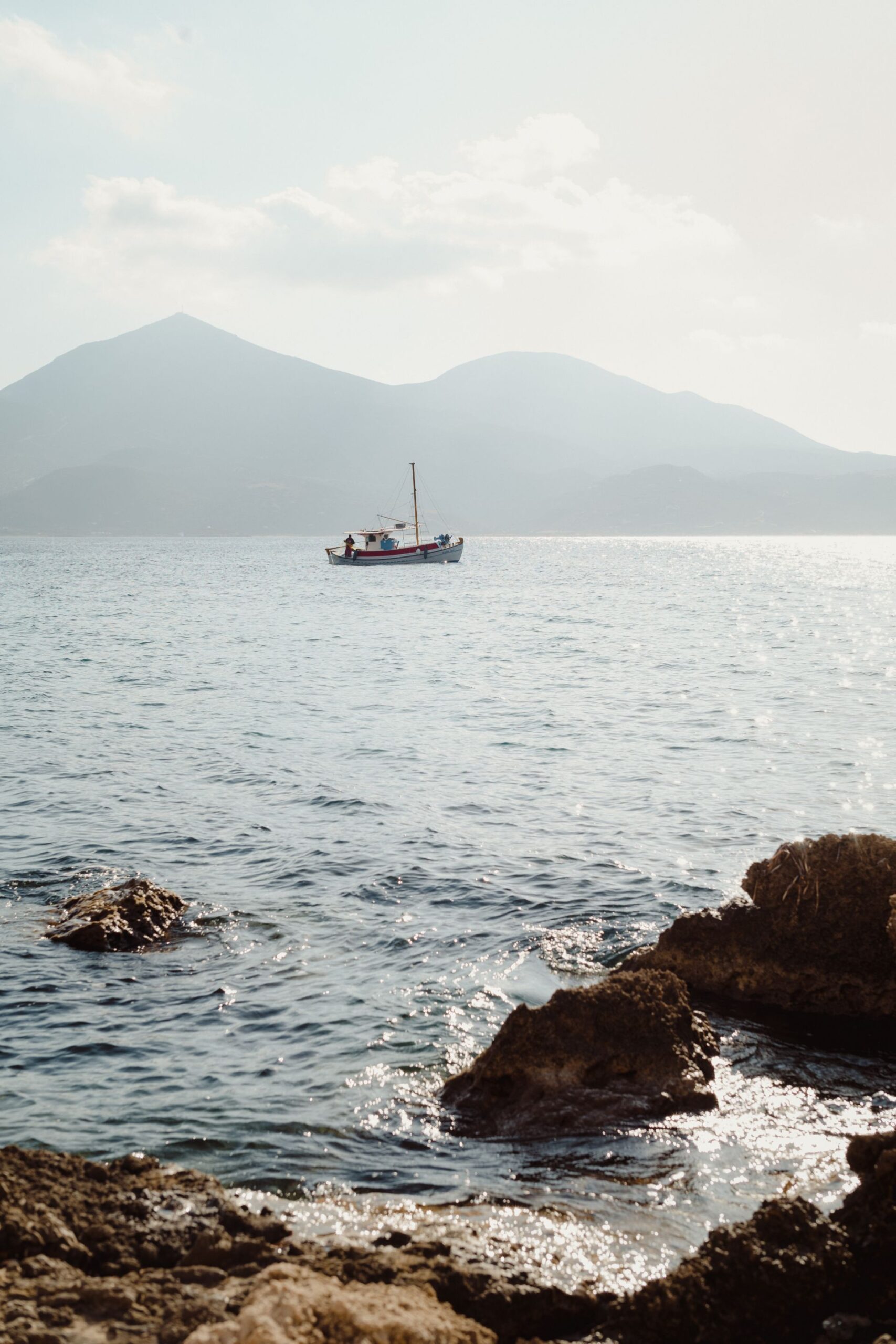The bare golden coastline and clear water of Milos