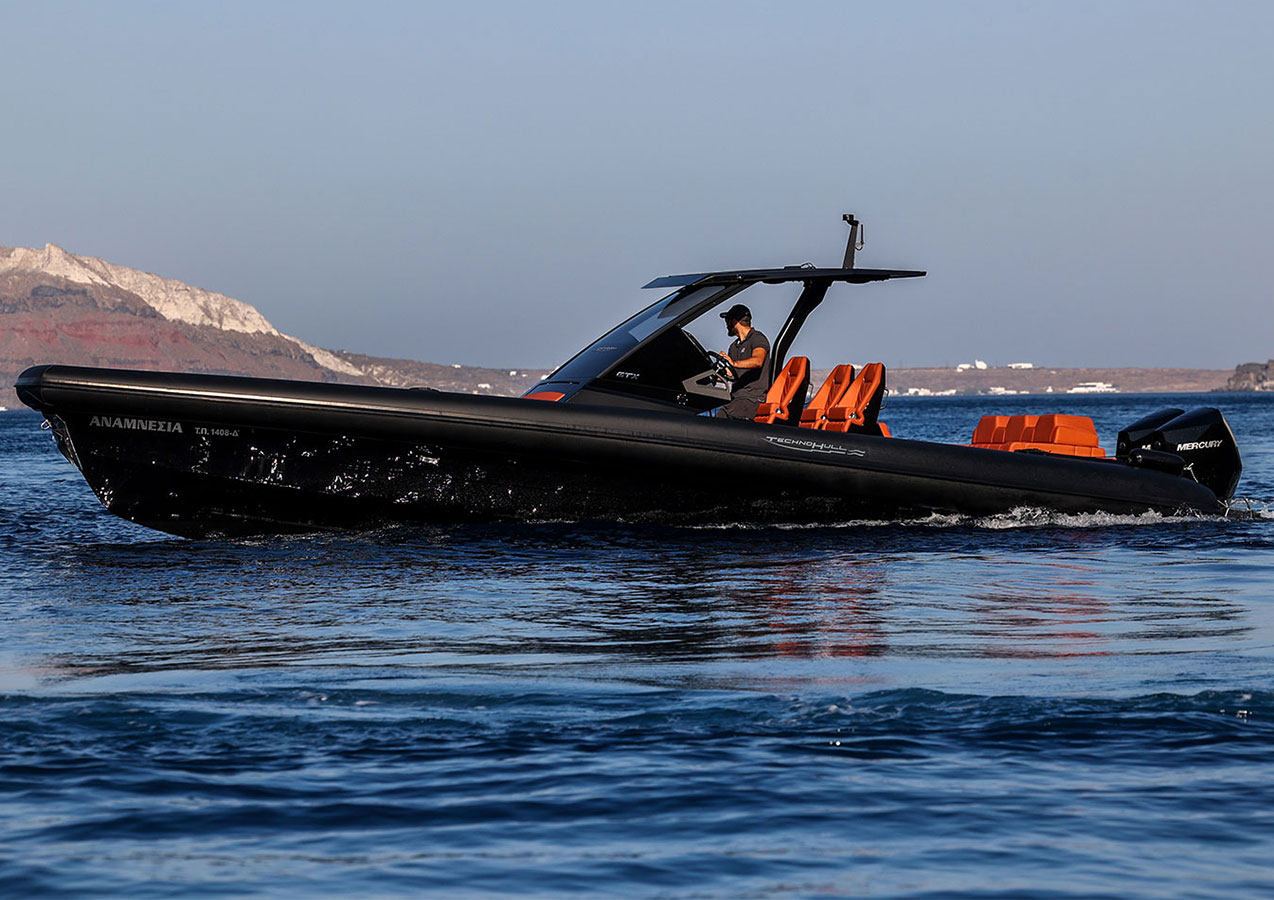 A captain at the helm of a black Technohull RIB off the Santorini coast