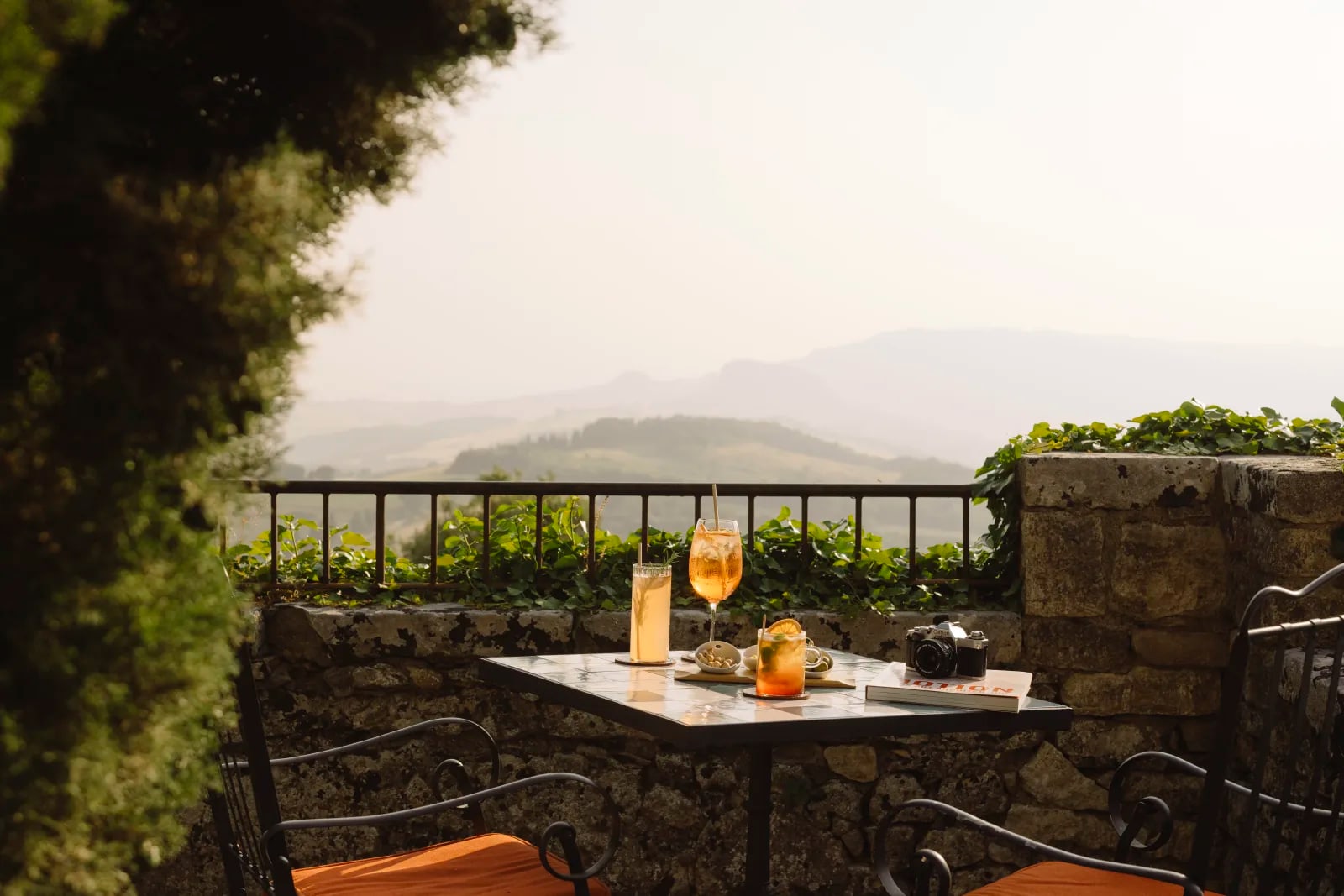 Aperitivo on a stone terrace at Borgo Pignano, looking out over the hazy valley