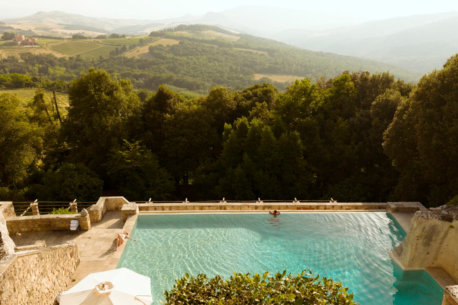 The infinity pool at Borgo Pignano, cut into the hillside above the woods and the valley